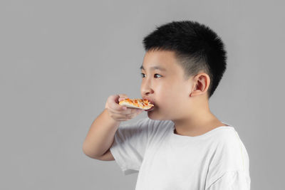 Portrait of boy eating food against white background