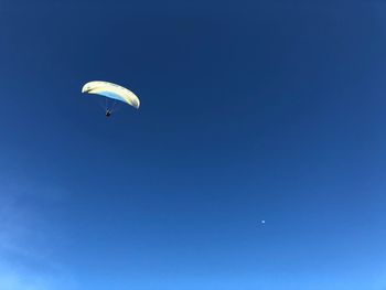 Low angle view of paragliding against blue sky