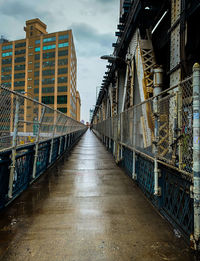 Footbridge amidst buildings in city against sky