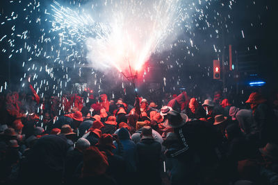 Low angle view of crowd at firework display at night