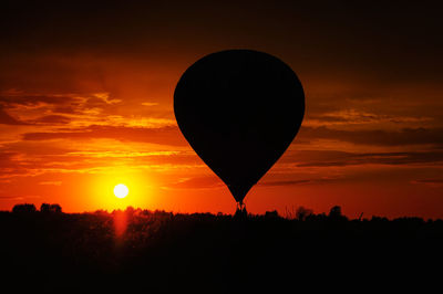 Silhouette hot air balloon against orange sky