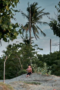 Rear view of woman sitting on field against sky