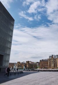 Street by buildings against sky in city