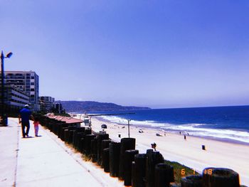 People on beach against clear sky