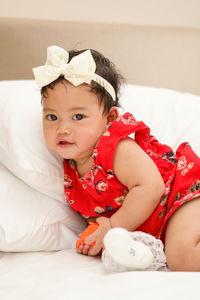 Portrait of cute baby girl lying on bed at home