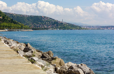 Scenic view of sea by townscape against sky