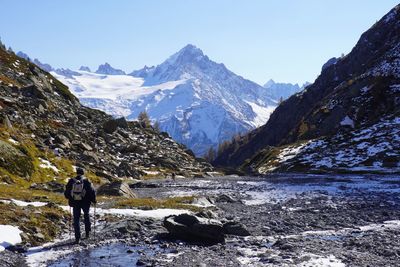 Rear view of person standing on snowcapped mountain against sky