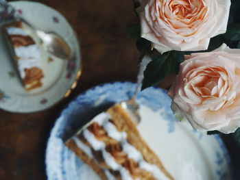 High angle view of roses by cake in plate at table