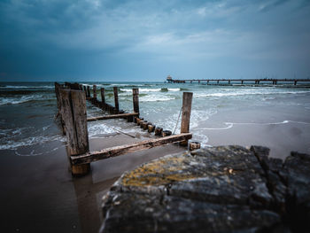 Wooden posts on sea against sky