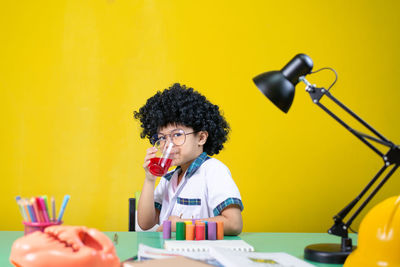 Portrait of young woman holding yellow while sitting on table