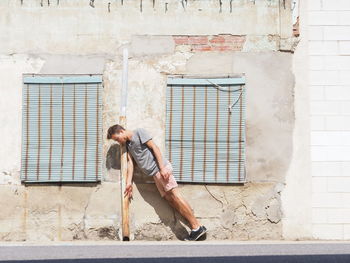 Full length of man leaning on pipe against building