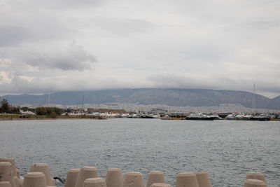 Sailboats in sea by city against sky