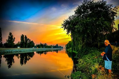 Silhouette of woman standing by river during sunset