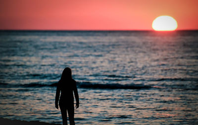 A woman looking at a beautiful sunset over the sea.