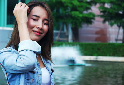 Beautiful young woman wiping sweat with tissue paper against fountain