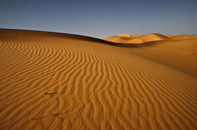 Sand dunes in desert against clear sky