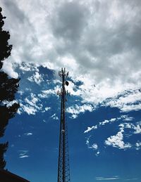 Low angle view of communications tower against cloudy sky