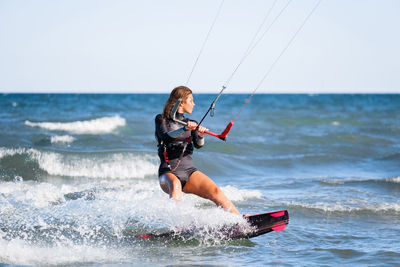 Full length of woman surfing in sea against clear sky