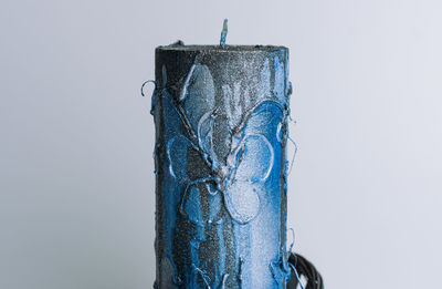Close-up of blue metal hanging against white background