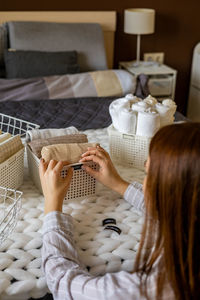 Rear view of woman sitting on bed at home