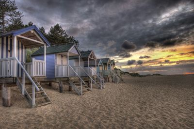 Log cabins on beach against cloudy sky during dusk at wells next the sea