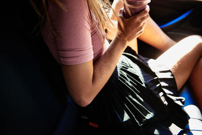 Midsection of young woman traveling in car