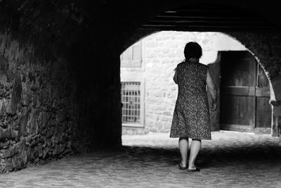 Rear view of woman standing against building in city