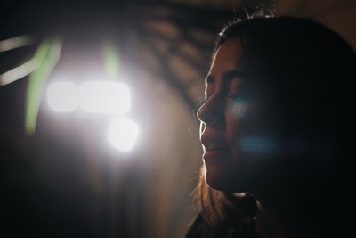 Close-up of young woman in illuminated room