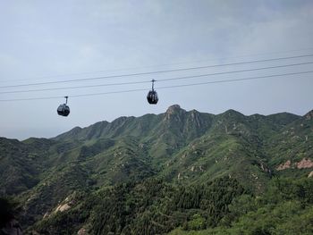 Overhead cable car over mountains against sky