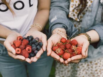 Midsection of women holding strawberries