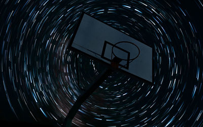 Digital composite image of basketball hoop against light painting in sky