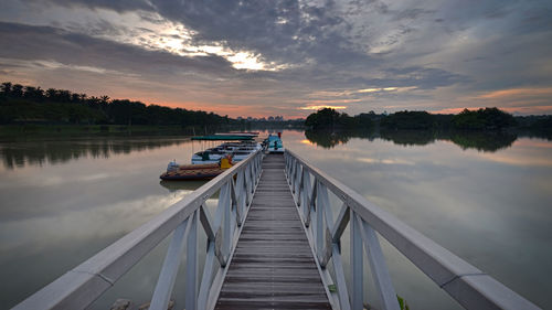 Jetty on lake against sky during sunset