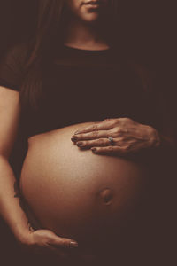 Midsection of pregnant woman over black background