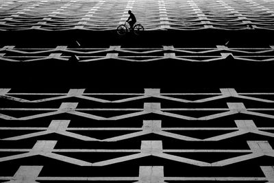 Side view of silhouette man cycling by lake against building