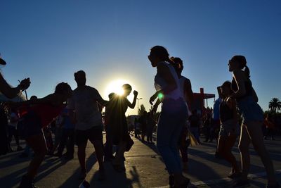 Low angle view of silhouette people against blue sky