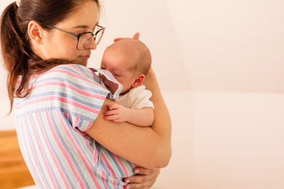 Side view of mother carrying daughter at home