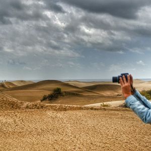 Cropped image of hand photographing through camera at maspalomas dunes