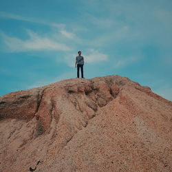 Rear view of man standing on rock against sky