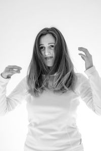 Portrait of woman holding camera while standing against white background