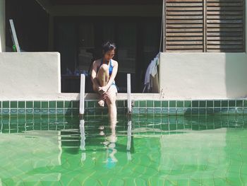 Mature woman resting while sitting by swimming pool