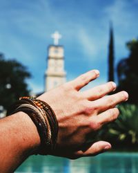 Close-up of human hand against blurred tower