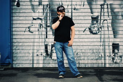 Man smoking while standing graffiti on wall