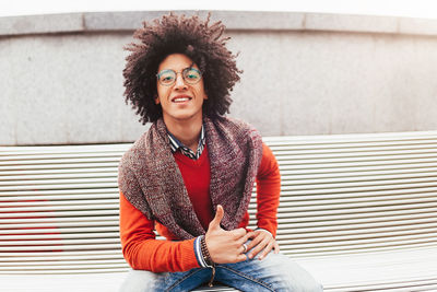 Portrait of smiling young man with afro hairstyle sitting in city