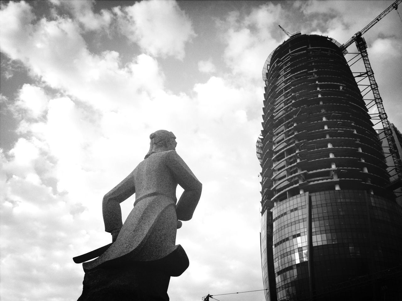 low angle view, sky, building exterior, cloud - sky, architecture, built structure, city, tall - high, cloudy, modern, cloud, skyscraper, sculpture, statue, tower, office building, human representation, building, outdoors, day