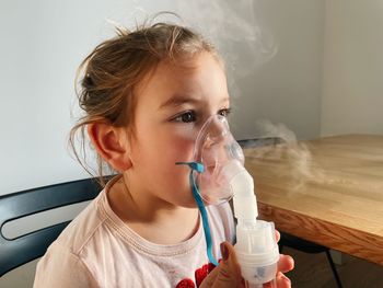 Cute girl wearing nebulizer at clinic