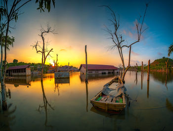 Sailboat moored in lake against sky during sunset