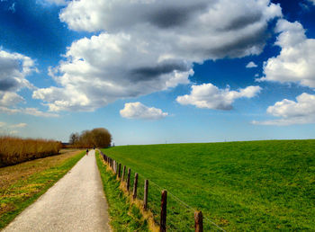 Road amidst field against sky