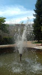 Man splashing water in swimming pool against sky