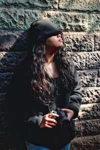 Beautiful young woman standing against wall