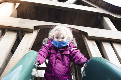 Low angel view of girl on slide at park during rainy season